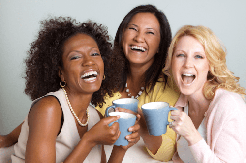 Photo of three women smiling with coffee cups